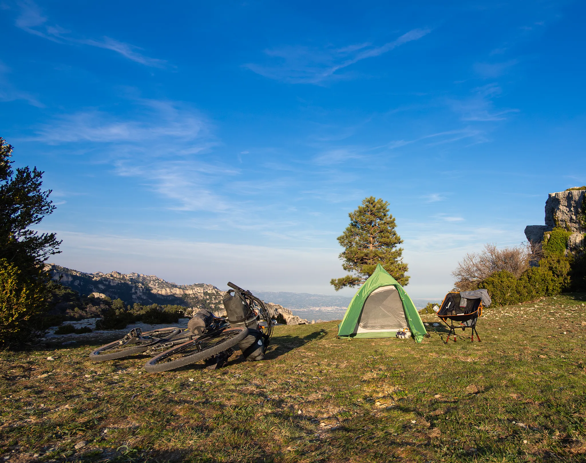 Tienda de campaña junto a bicicleta de cicloturismo en planicie con vistas al Delta del Ebro