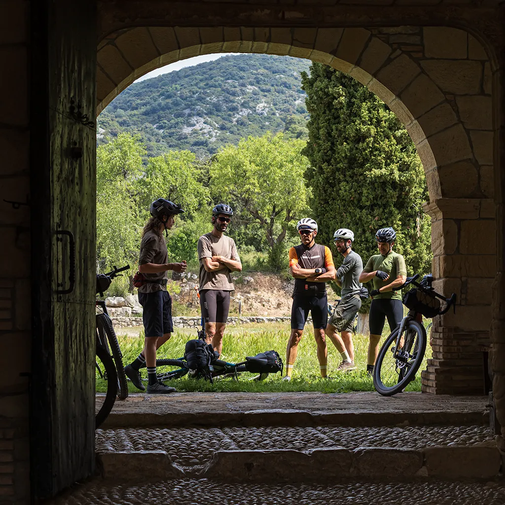 Ciclistes descansant en una entrada en arc de pedra
