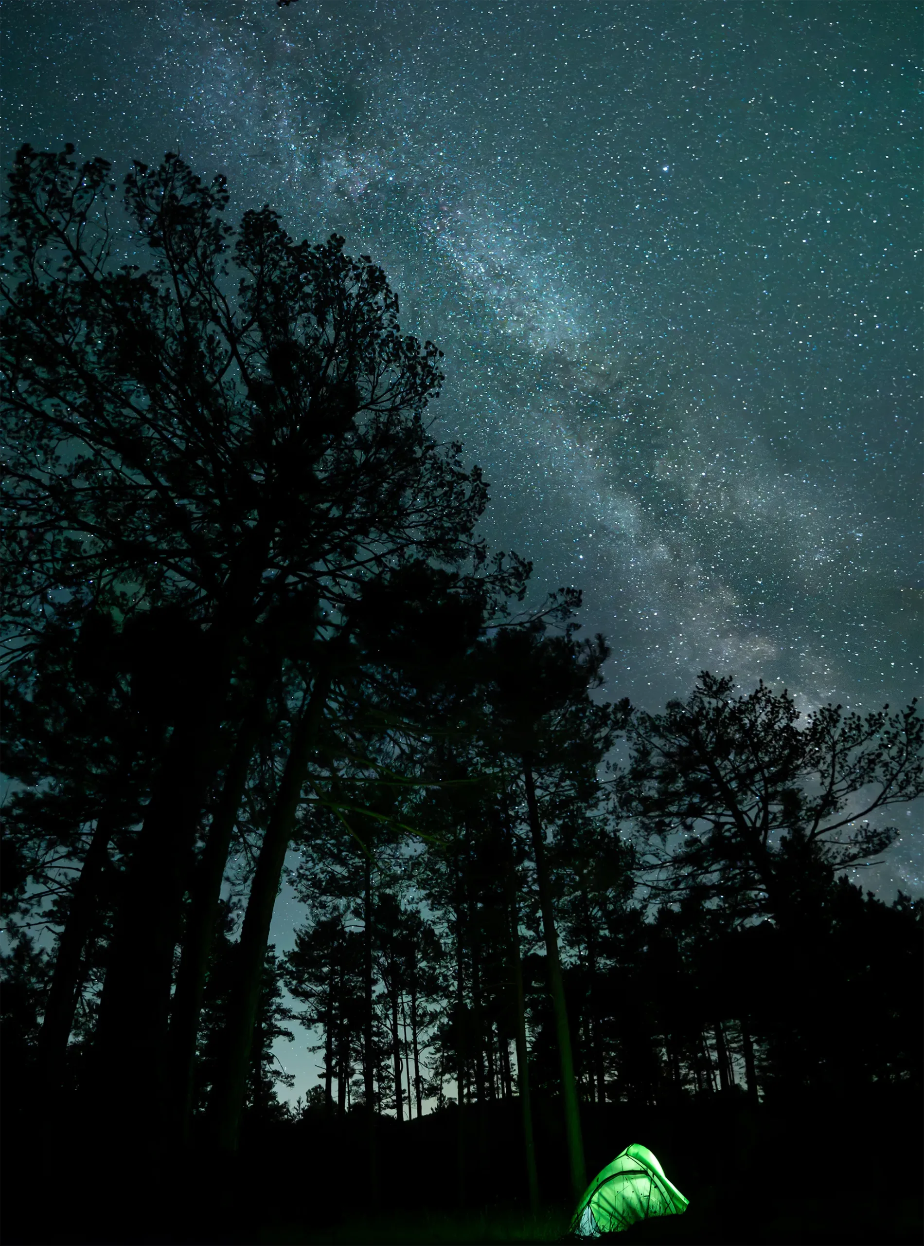 Fotografía nocturna de una tienda de campaña iluminada en mitad de la noche y la vía láctea sobre ella