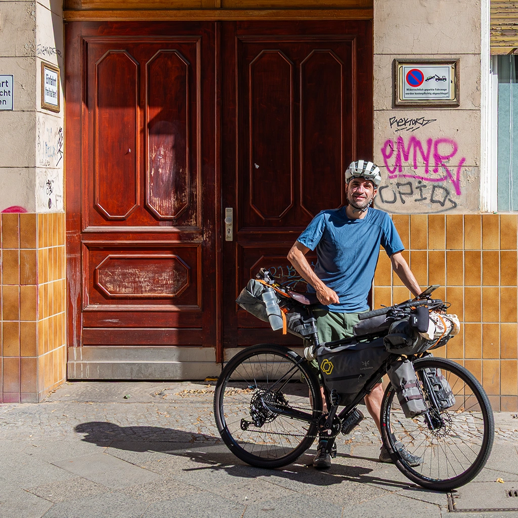 Cicloturista enfrente de un portal en Berlín con bicicleta de gravel y alforjas de bikepacking