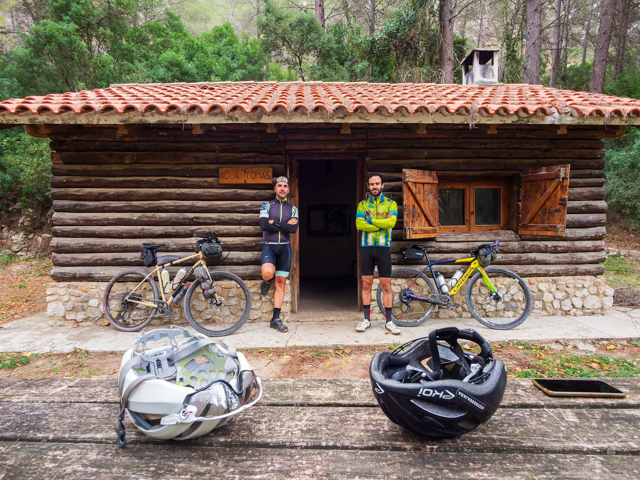 Cicloturistas posando con sus bicicletas apoyadas en la pared del refugio