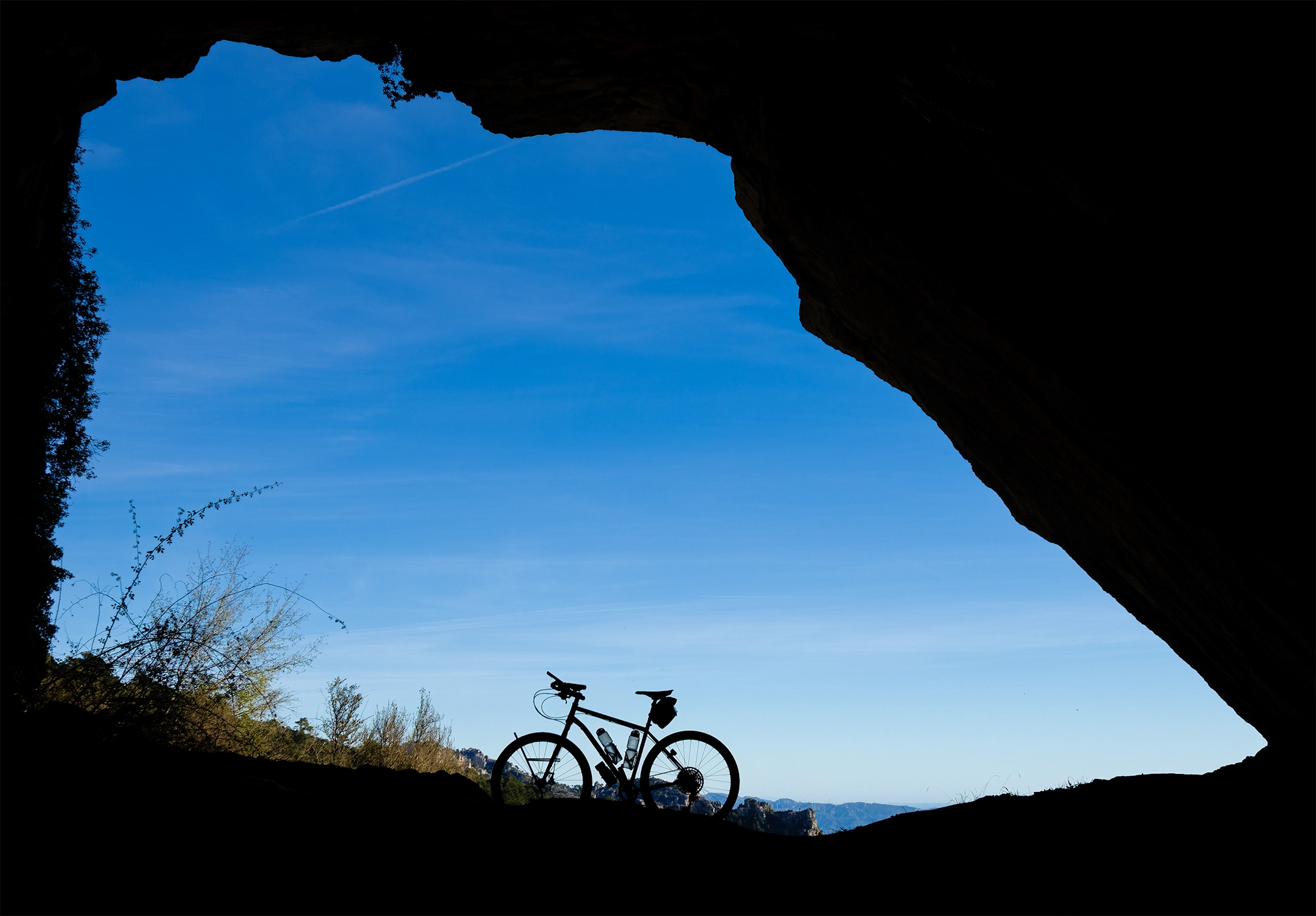 Bicicleta en medio de la entrada de una cueva enorme situada en el parque natural de Els Ports